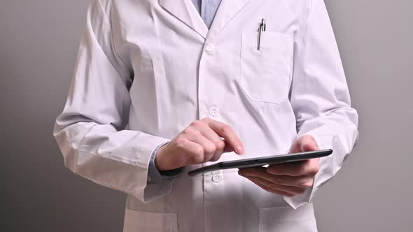 Caucasian male doctor dressed in a white coat holding a tablet.