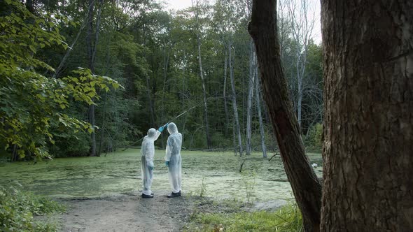 People Wearing Protective White Suits Taking Soil and Water Samples for Testing