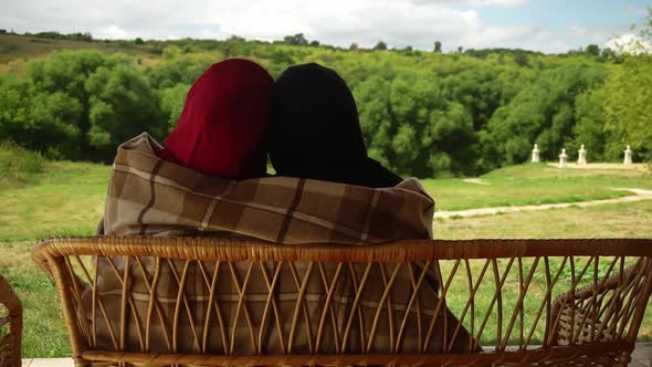 Back View of Man and Woman Who are Sitting on a Bench and Hugging Covered By a Blanket