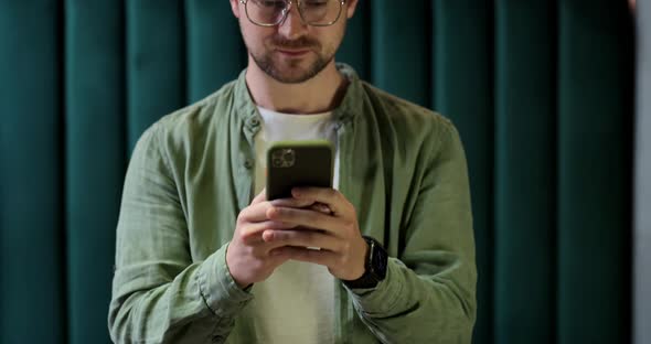 Portrait of Caucasian Man Using Smartphone and Looking at Camera