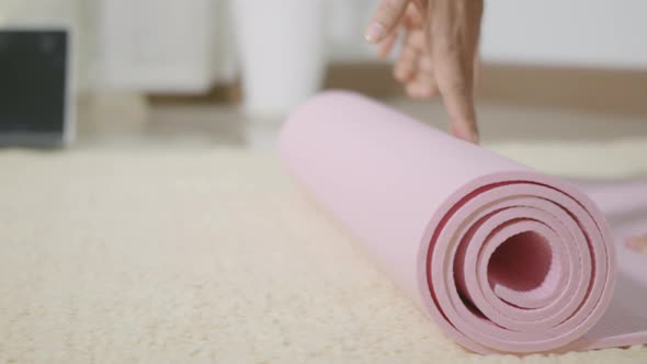 woman rolling fitness yoga pink mat before sports practice for exercise