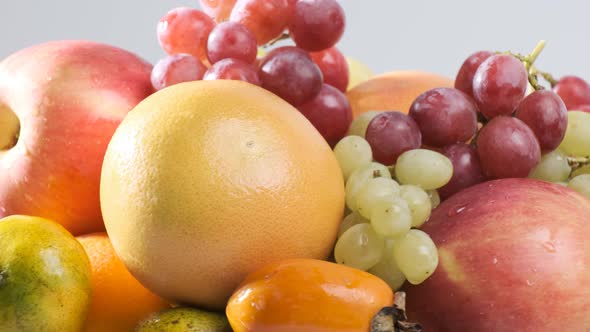 Various types of fresh fruits on white plate rotating in front of camera