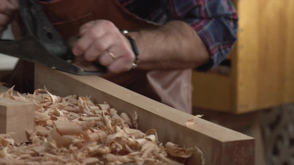 Cabinet Maker Planes Solid Wood in his Workshop