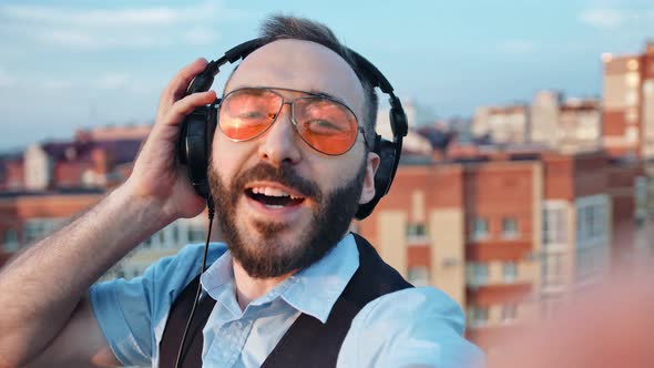 Professional Male DJ with Headphones on Head and in Sunglasses Taking Selfie at Rooftop Party