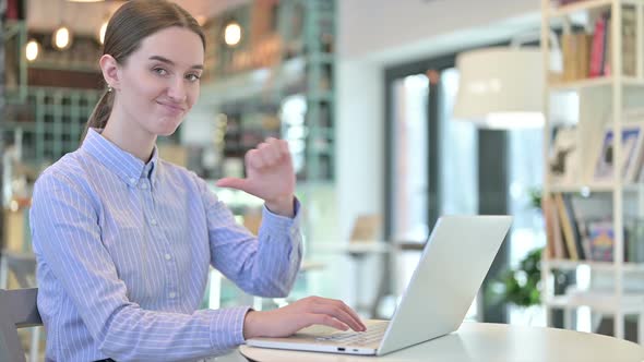 Thumbs Down By Young Businesswoman Using Laptop in Cafe