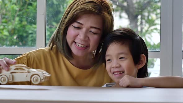 Asian Mother And Son Playing Wood Toy Car Together