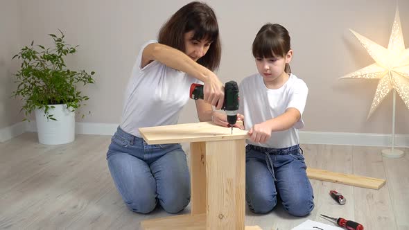 Happy Family Mother and Daughter Assembling Wooden Furniture Together with Screwdriver