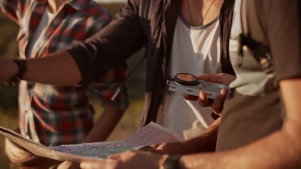 Three Friends with Map and Compass Trying to Find Way in Prairie