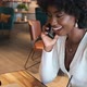 Happy African American Woman Sitting in Cafe with Coffee Talkin on Phone - VideoHive Item for Sale