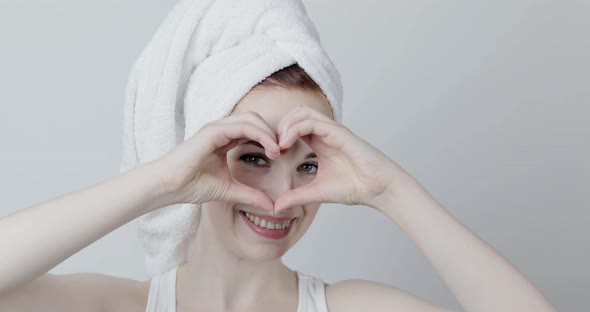 Woman with Towel on Head Dancing and Looking at Camera Through the Heart Gesture