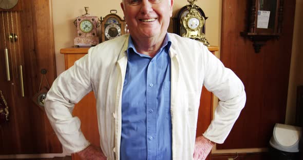 Portrait of smiling horologist standing with arms crossed