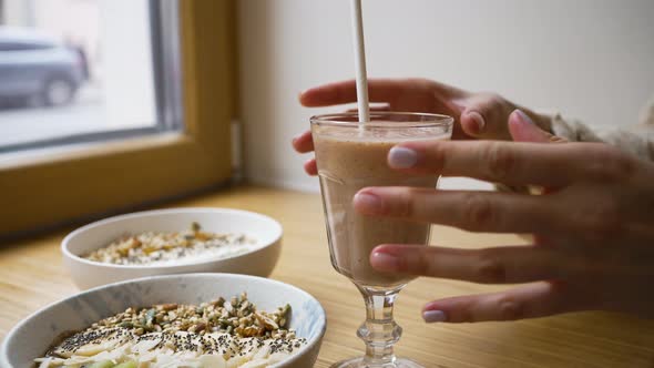 Female Hands Take Glass of Fresh Smoothie From Wooden Table