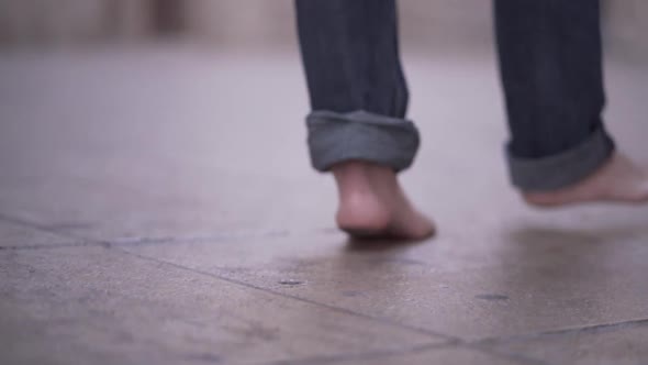 Follow Shot of Barefoot Man Walking Around the City Wearing Jeans