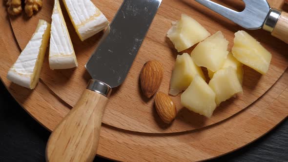 Sliced Cheese, Nuts and Knife on Wooden Platter. Rotating