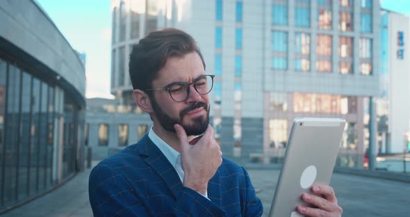 Business Man Looks at the Tablet Choosing Makes a Decision