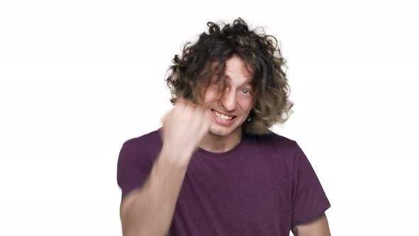 Portrait of Ecstatic Guy with Curly Hair in Casual Tshirt Rejoicing and Clenching Fists in Joy