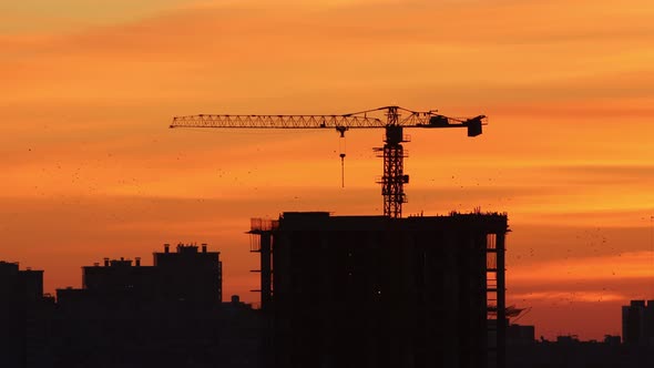 Early Dawn - Morning Sky of Red and Orange Shades - Silhouettes of Buildings and Lifting Crane