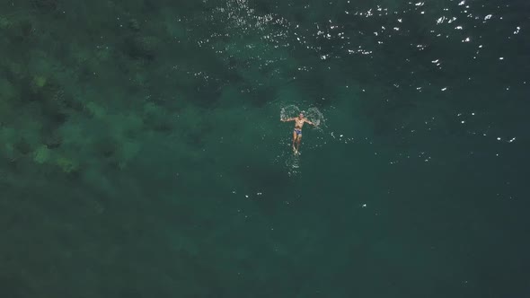 A Fit Young Man Enjoys Swimming Anf Floating in the Blue Ocean at Summer