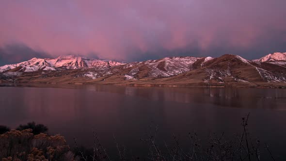 Time lapse of low clouds lighting up as sun rises and shines on mountain