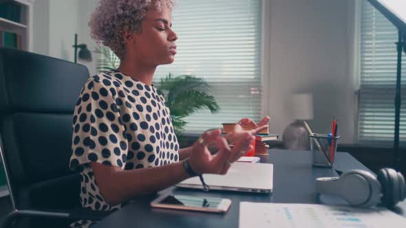 African American Woman Entrepreneur Meditates in Yoga Position at Workplace