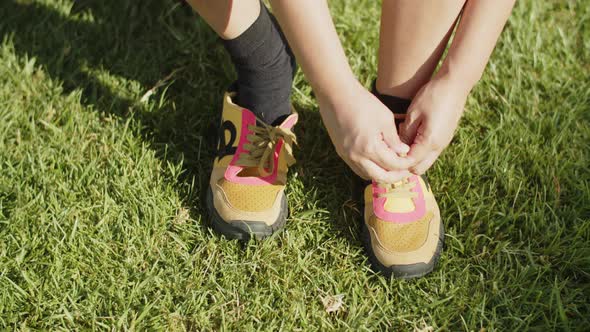 Medium Shot of Woman Lacing Up Sneakers in Summer Park