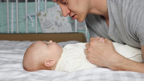 Young Father Speaks to Baby Girl Holding Tiny Child Hand