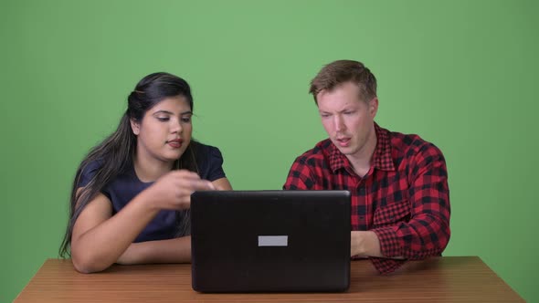 Young Multi-ethnic Business Couple Together Against Green Background