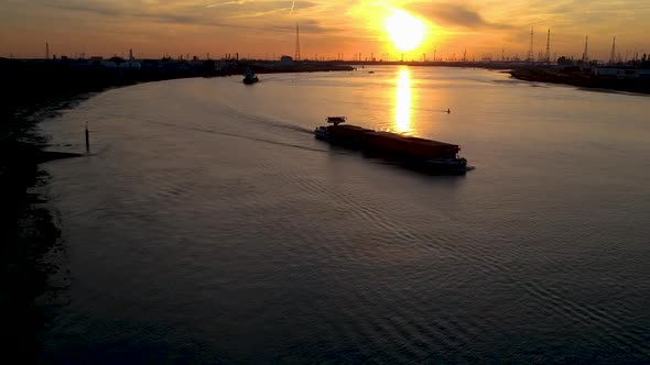 Cargo ships leaving the international port of antwerp at sunset. Tilt down drone shot.