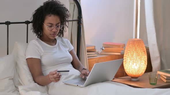 Online Shopping Success on Laptop By Young African Woman on Sofa