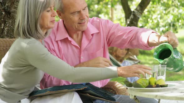 Mature couple in garden eating and looking at photo album memories