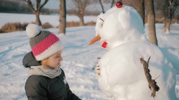 Happy Girl Builds a Snowman in Winter Park