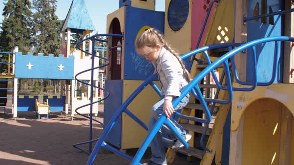 Junior Schoolgirl in Pullover Climbs Up Metal Attraction