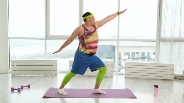 Funny Fat Man Doing Yoga Exercises in Bright Room