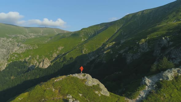 Climber with Orange Jacket Hiking on Rocky Edge in Balkan Mountains