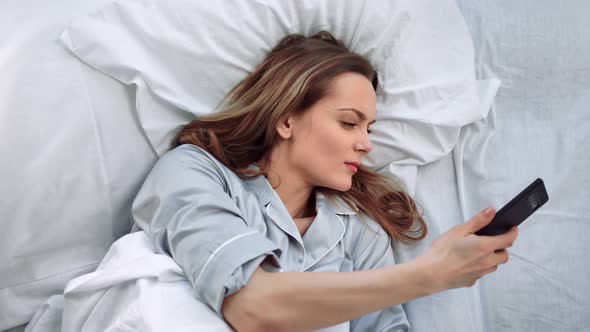 Sleeping Woman Lying on Bed Awaking From Mobile Call at Morning