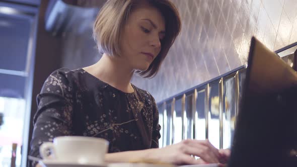 Woman Working on Her Laptop and Enjoying Her Coffee