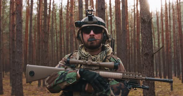 Portrait of a Middleaged Bearded Soldier in a Woodland Military Uniform and Helmet with Headphones