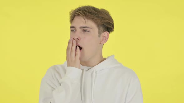 Young Man Yawning on Yellow Background
