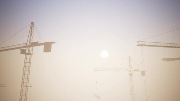Construction Cranes In The Sunset Scene With The Passing Of A Plane alt