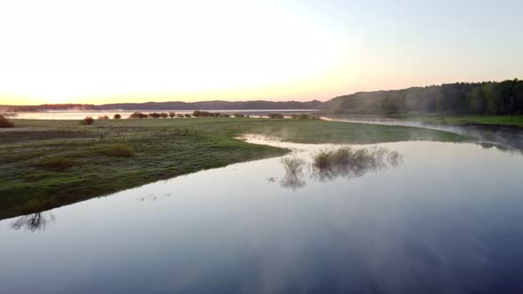 Flying Over the River in the Morning Steam From the Water and a Bright Sky Shooting From a Drone