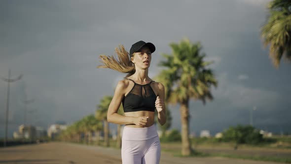 A Young Woman Runner is Training in the Summer Within a City