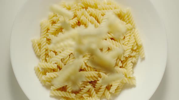 SLOW MOTION: Fusilli Pasta Falling Into A White Plate - Top View