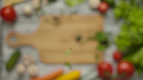 Parsley and Basil Leaves Falling on Chopping Board