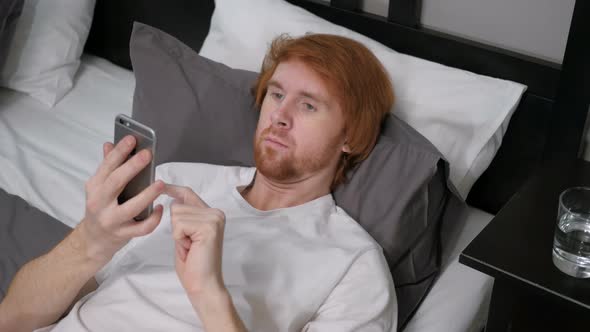 Man Lying in Bed Using Internet on Smartphone