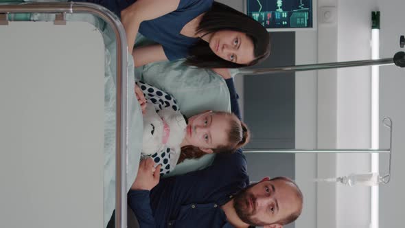 Vertical Video Portrait of Worried Family Looking Into Camera in Hospital Ward During Therapy