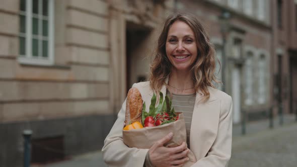 Smiling Woman Holding Grocery Bag While Standing Outdoors