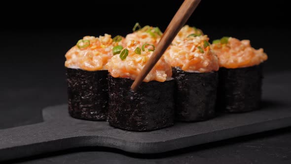 Take One Sushi Roll From Black Slate Board Using Chopsticks
