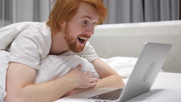 Excited Amazed Man in Bed Working on Laptop