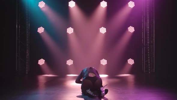 Woman Training Strip Plastic on the Floor in a Studio. Sensual Blonde Moving on a Black Background