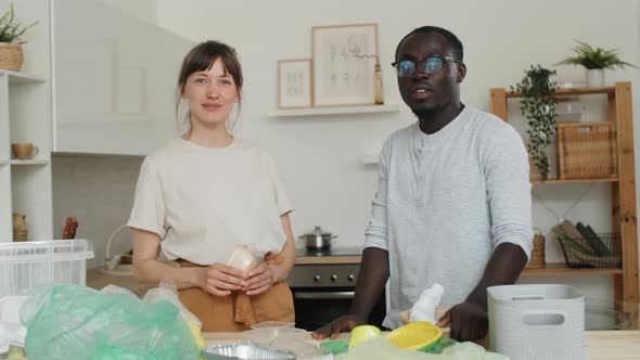 Young Multiethnic Couple Posing for Camera while Sorting Waste